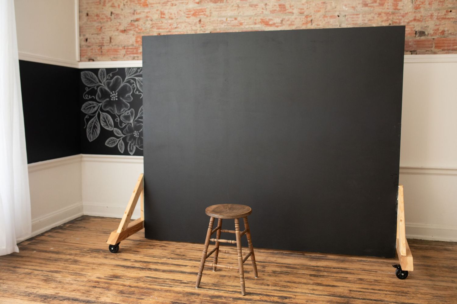 A chalkboard wall spans across a room with exposed brick walls and hardwood flooring.