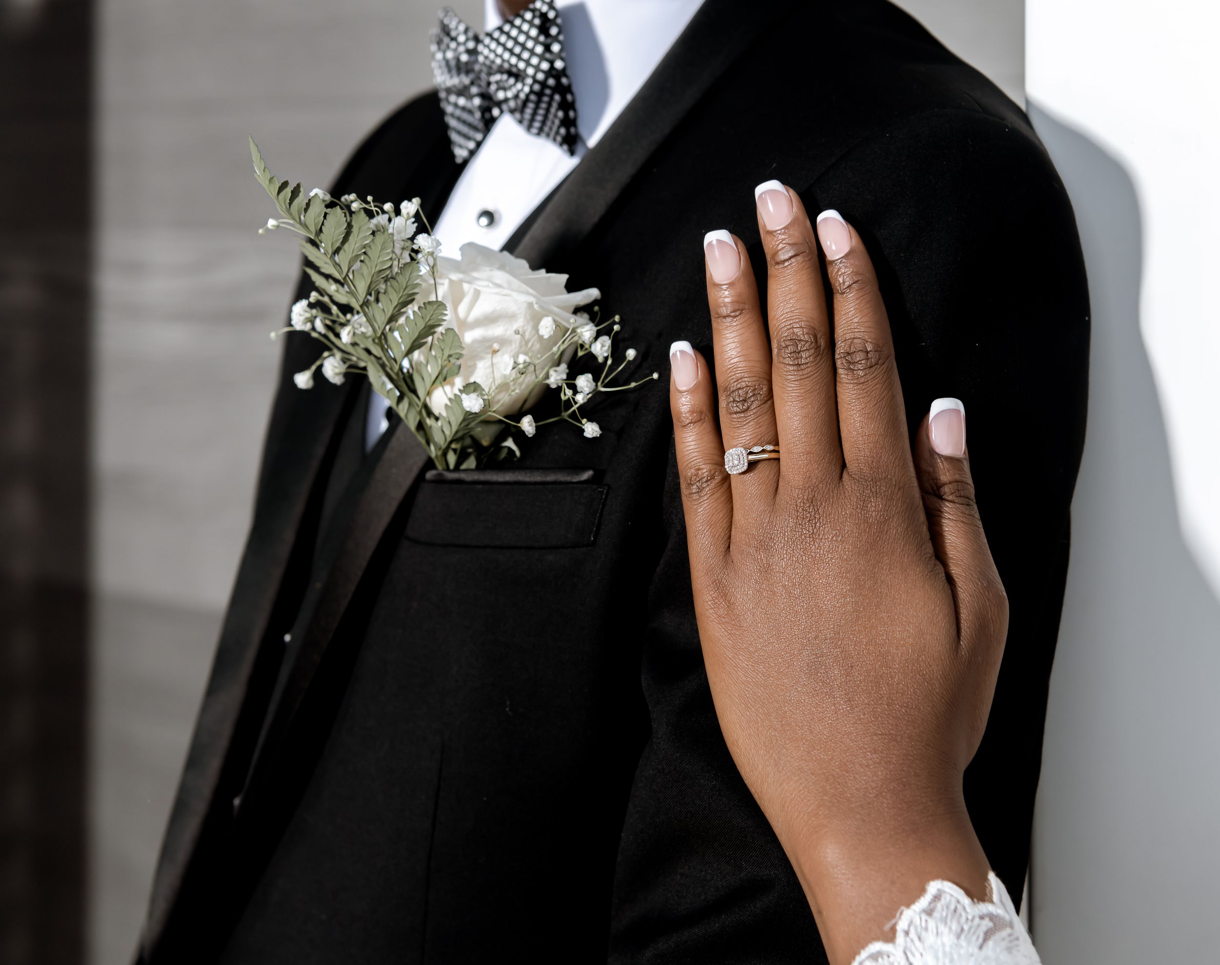 "Gros plan sur une main avec une alliance reposant sur le costume élégant du marié, capturé par Payo Studio lors d'un mariage."