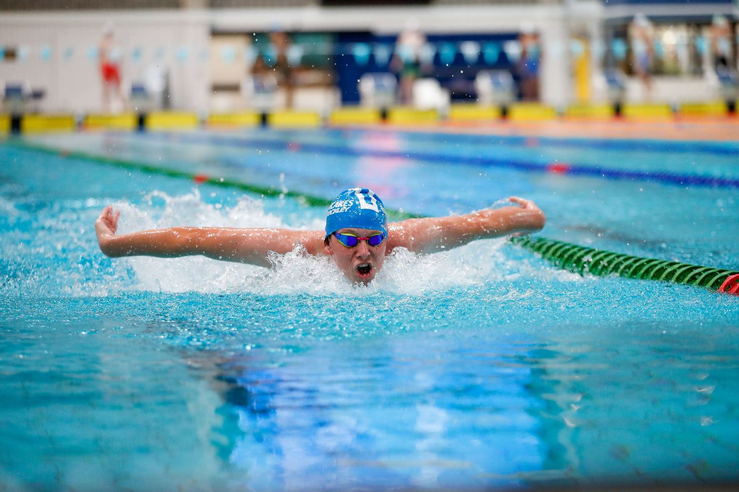 Swimmer executing butterfly stroke during competitive swimming event.