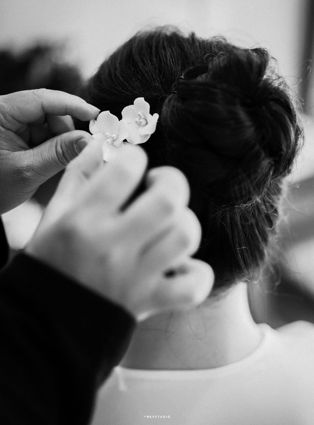 Black and white photo of hands placing floral hair accessories.