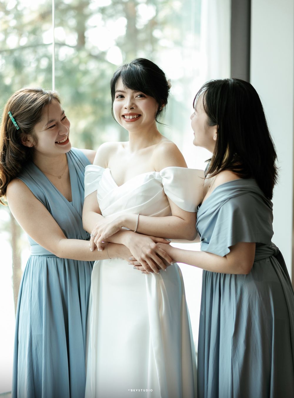 Bridesmaids in blue dresses share a joyful moment with the bride in white.