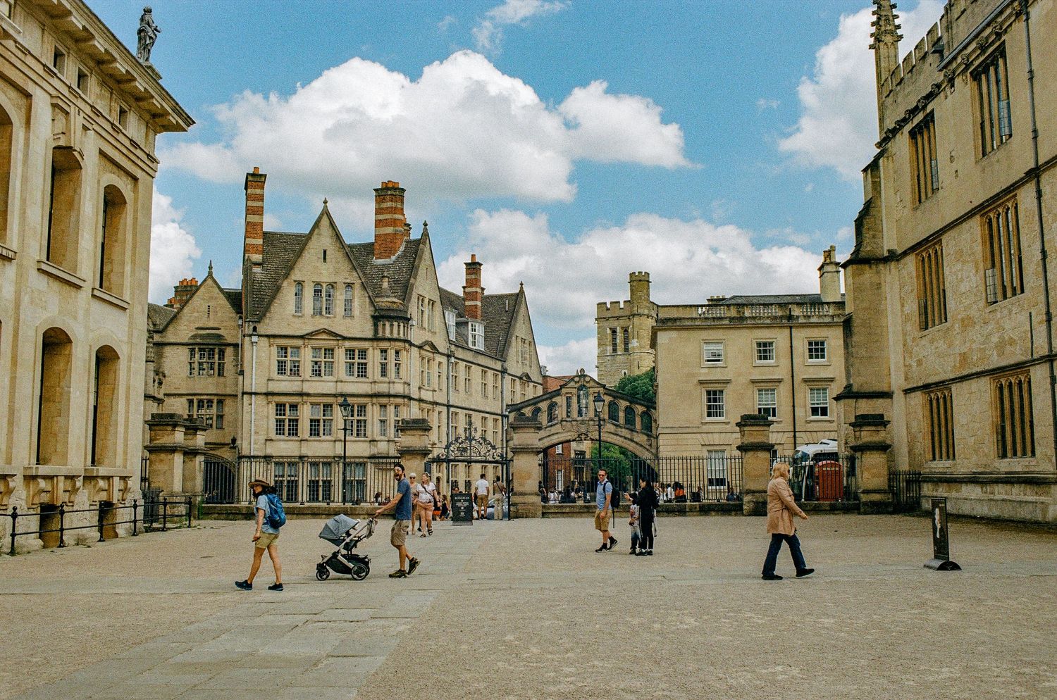 Historic architecture in Oxford city center with pedestrians crossing a cobblestone plaza.