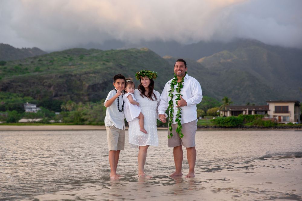 A family standing together on a beach with misty mountains in the background in Hawaii Kai.