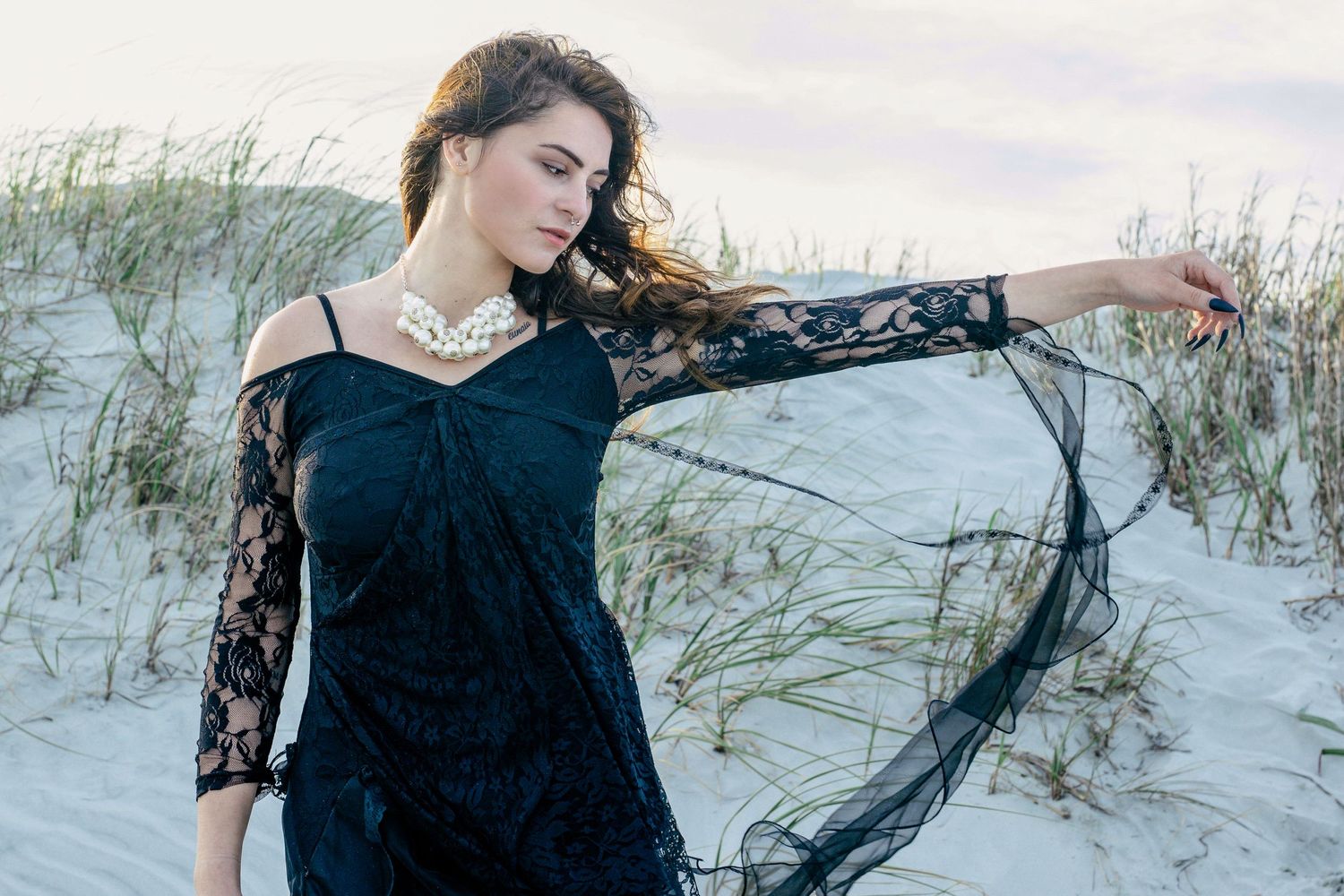 Elegant woman in black dress with long hair walking along the beach at golden hour – romantic portrait Windsor, Ontario.