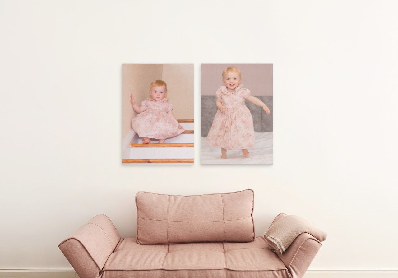 Blush pink sofa with throw pillows beneath framed family photographs.