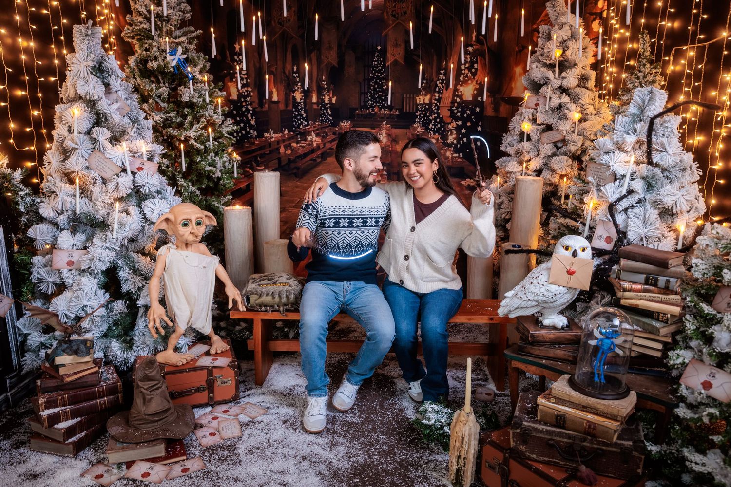 Holiday photoshoot setup with Christmas trees and decorative lighting in cozy indoor setting.