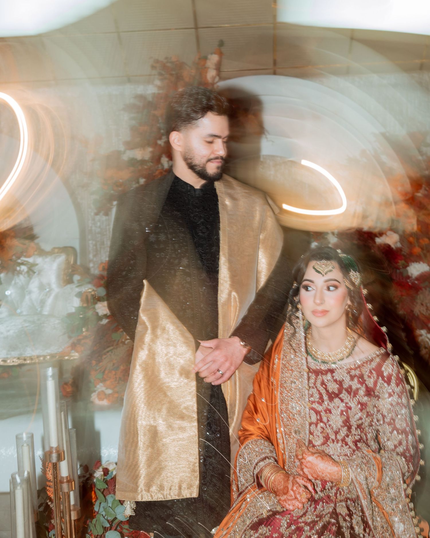 Hand adorned with intricate henna designs and bangles holds elegant white rose and baby's breath wedding bouquet.