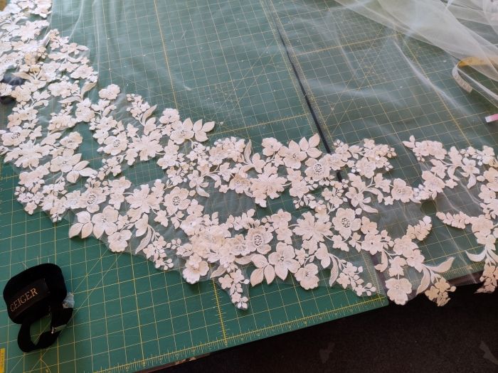 Mit Blumenspitzen bestickter Schleier auf einer grünen Arbeitsmatte