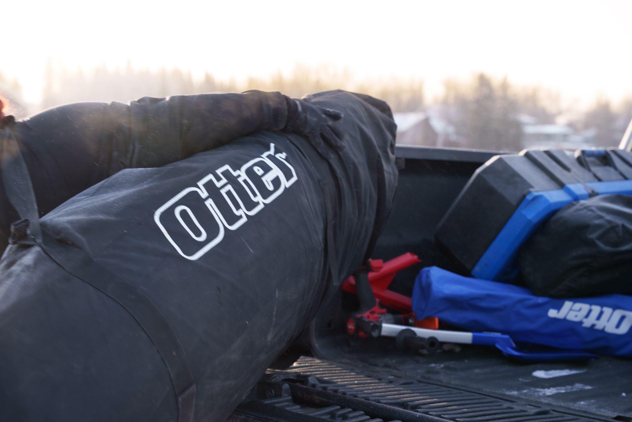 Racing gear including black motorcycling clothing with branding lies on a surface during sunset lighting conditions.
