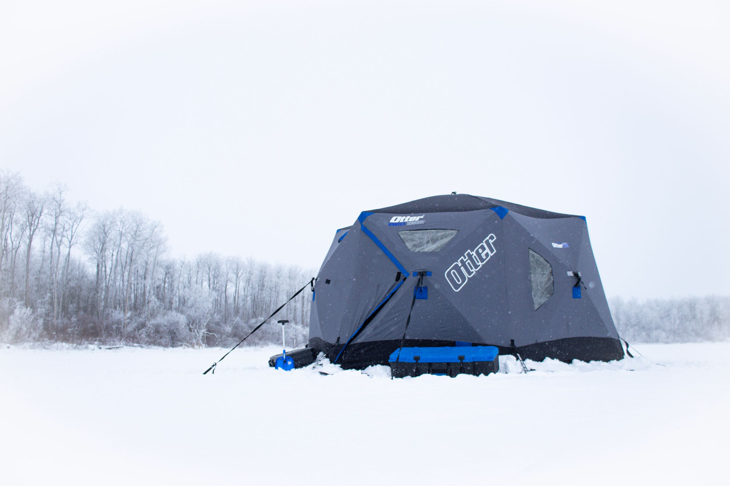 Blue ice fishing shelter on snow-covered lake in winter.