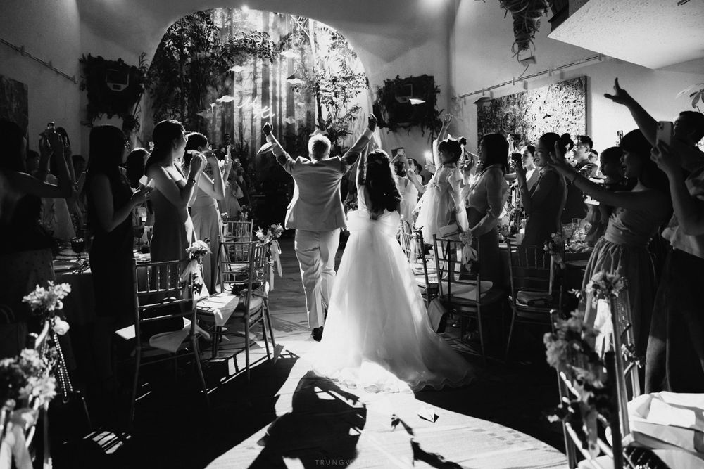 Bride and groom raising hands as they walk down the aisle at their wedding reception.