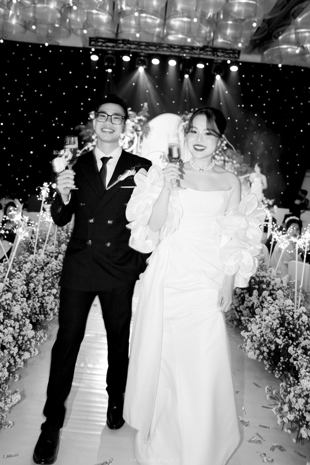 Black and white photo of a bride and groom toasting champagne at their wedding reception.
