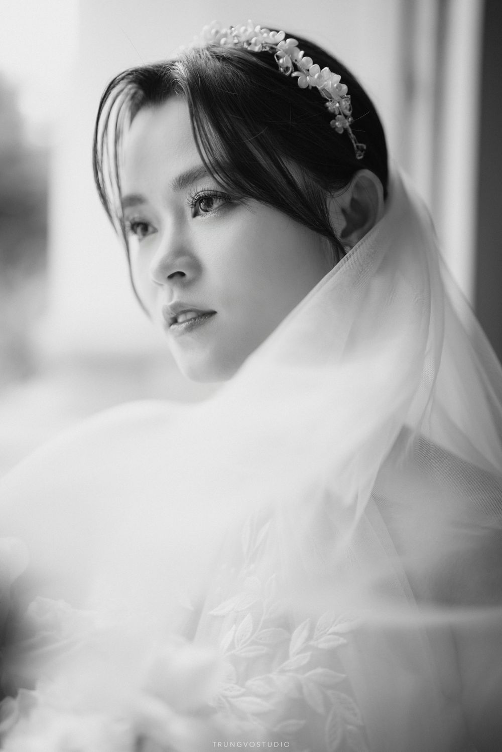 Black and white close-up portrait of a bride wearing a floral headpiece and veil.
