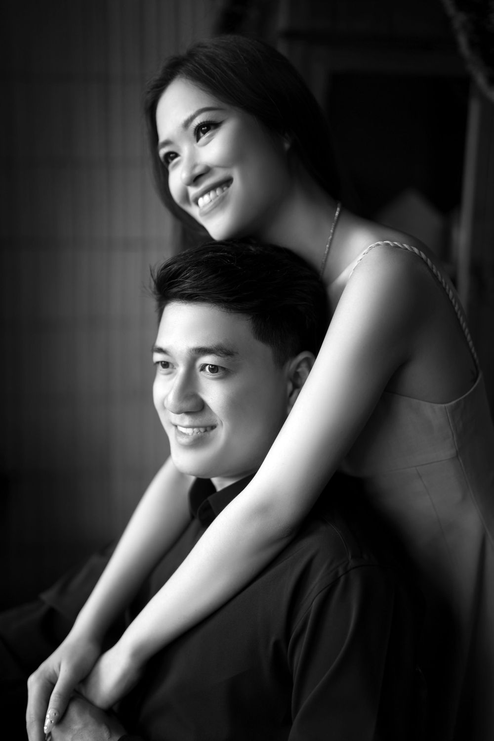 Black and white portrait of a smiling couple posing together in a casual setting.