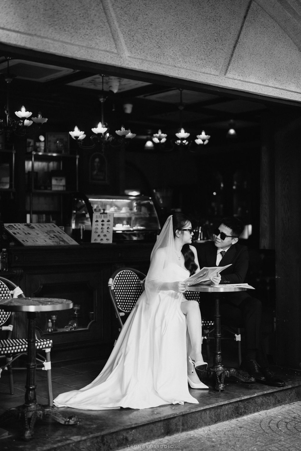 Black and white photo of a bride and groom sitting at a cafe table reading menus.