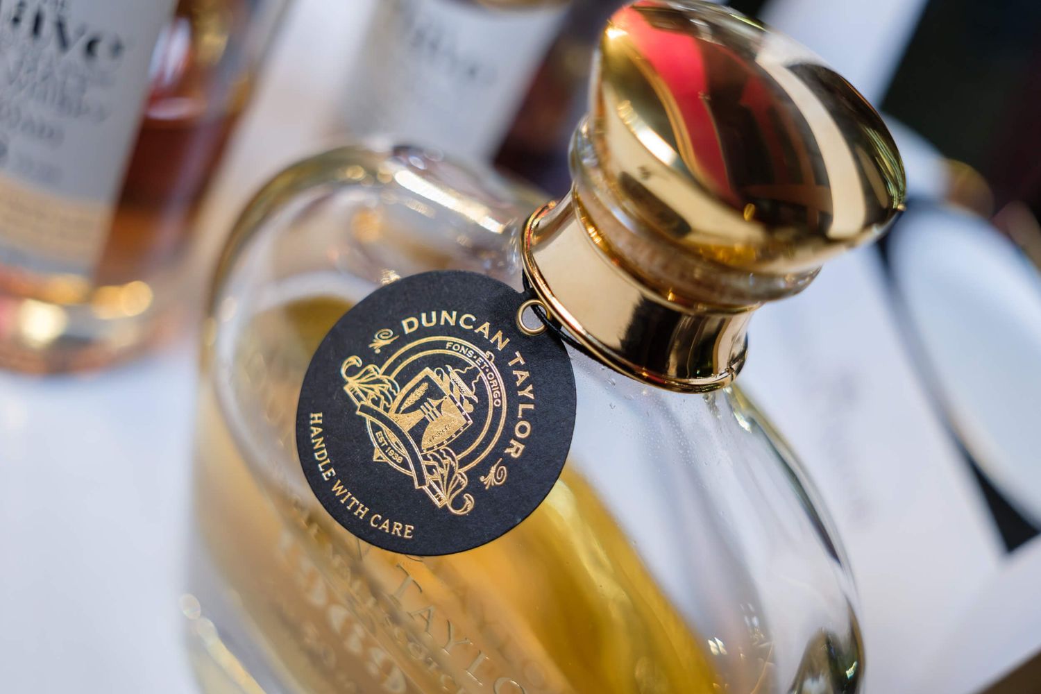 Wine bottles and glasses arranged on a table with elegant labels and golden details in warm lighting.