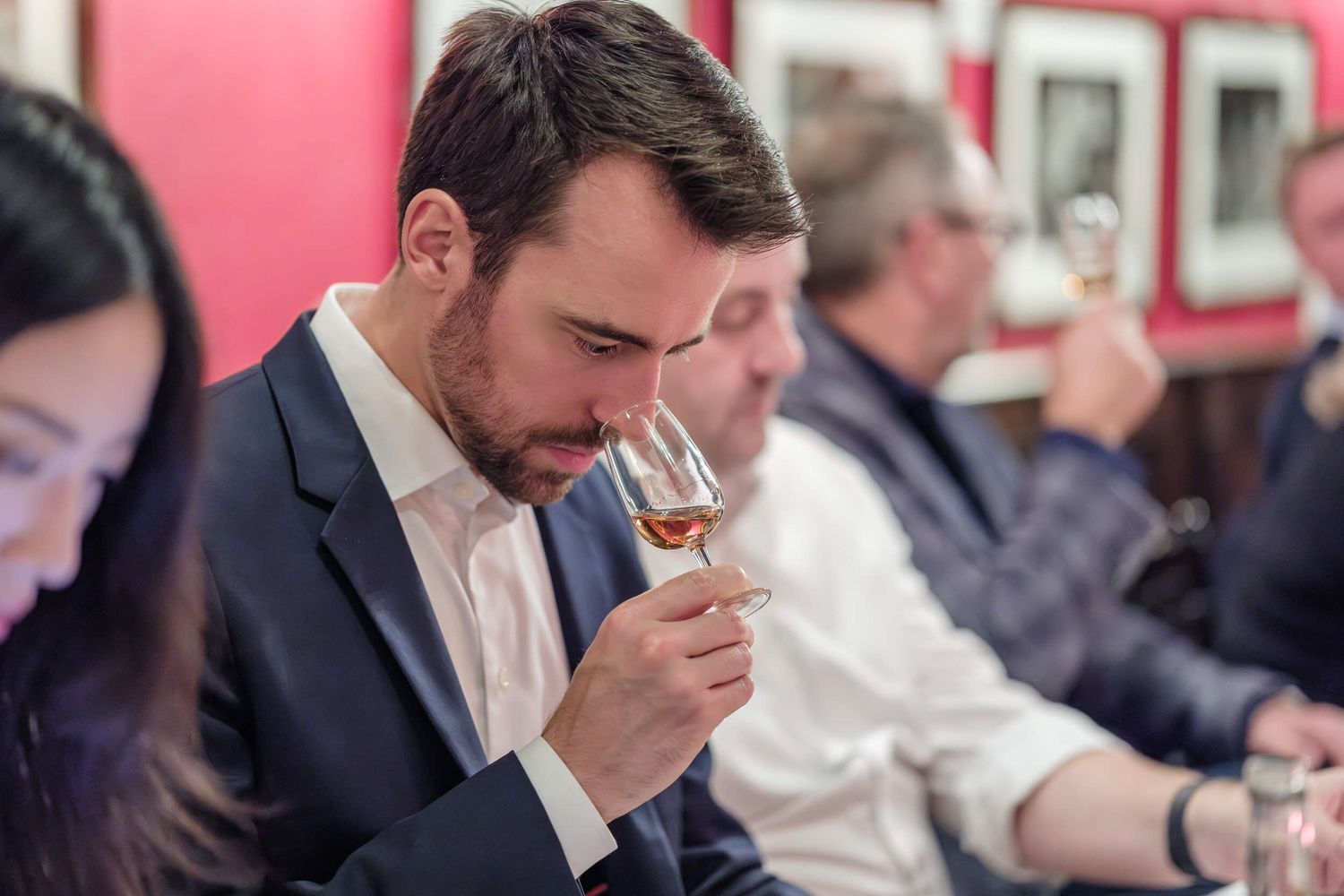 A sequence of four photos showing someone in a suit tasting wine at a formal event.