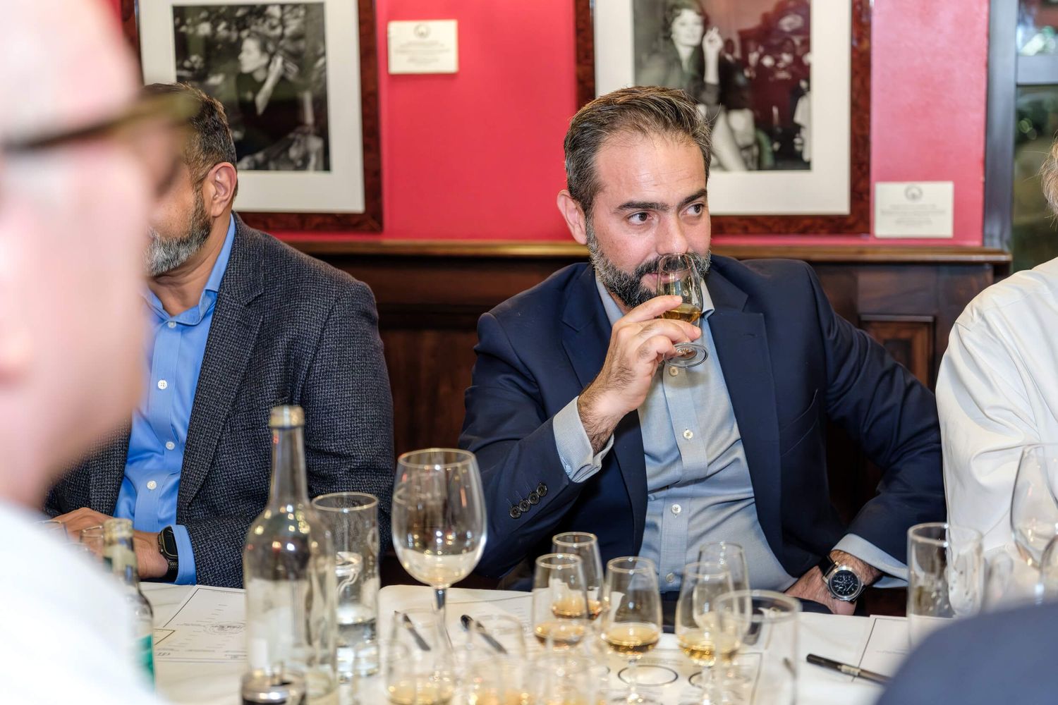 A group of people sit at a restaurant table with wine glasses and appear to be engaged in conversation.