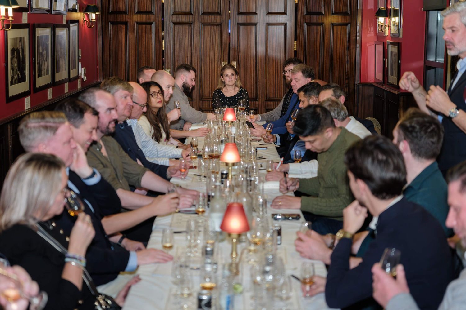 Diners seated at a long table in a restaurant with wood-paneled walls and warm lighting for a social gathering.