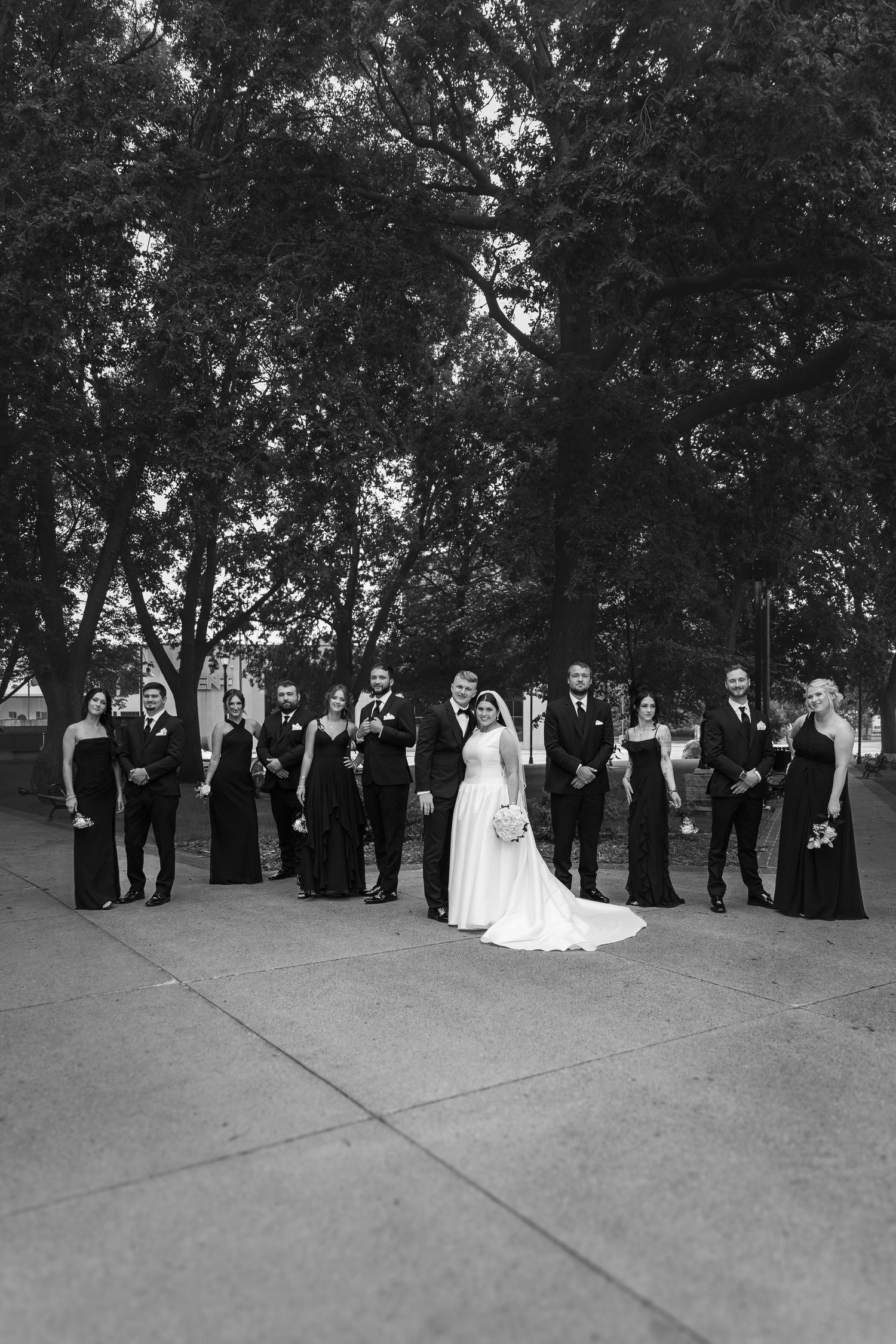 A black and white wedding party photo sequence showing the group gradually moving and changing positions outdoors.