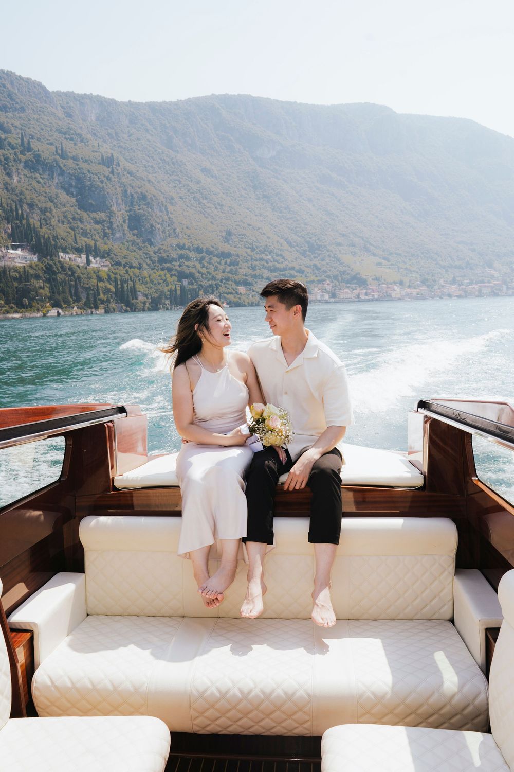 A couple enjoys a romantic boat ride on a lake surrounded by mountains and scenic views.
