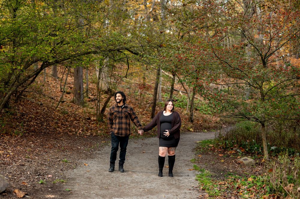Couple holding hands while walking on a winding path through an autumn forest.