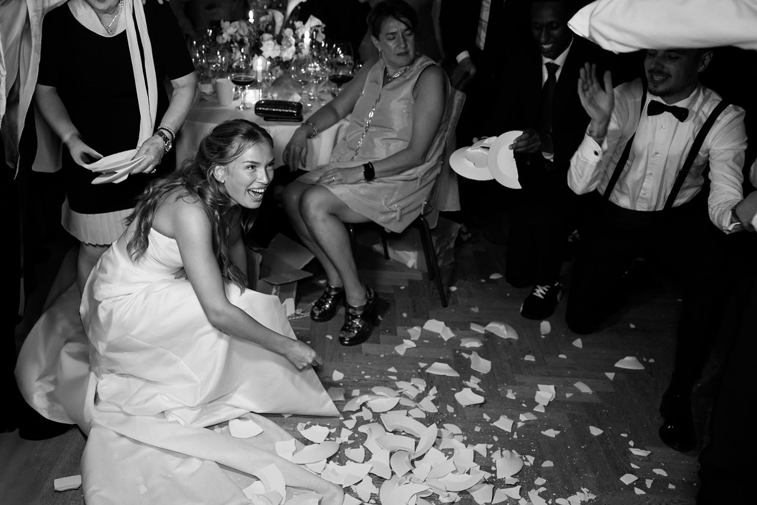 Wedding guests dance and celebrate on a confetti-covered dance floor during a lively reception party.