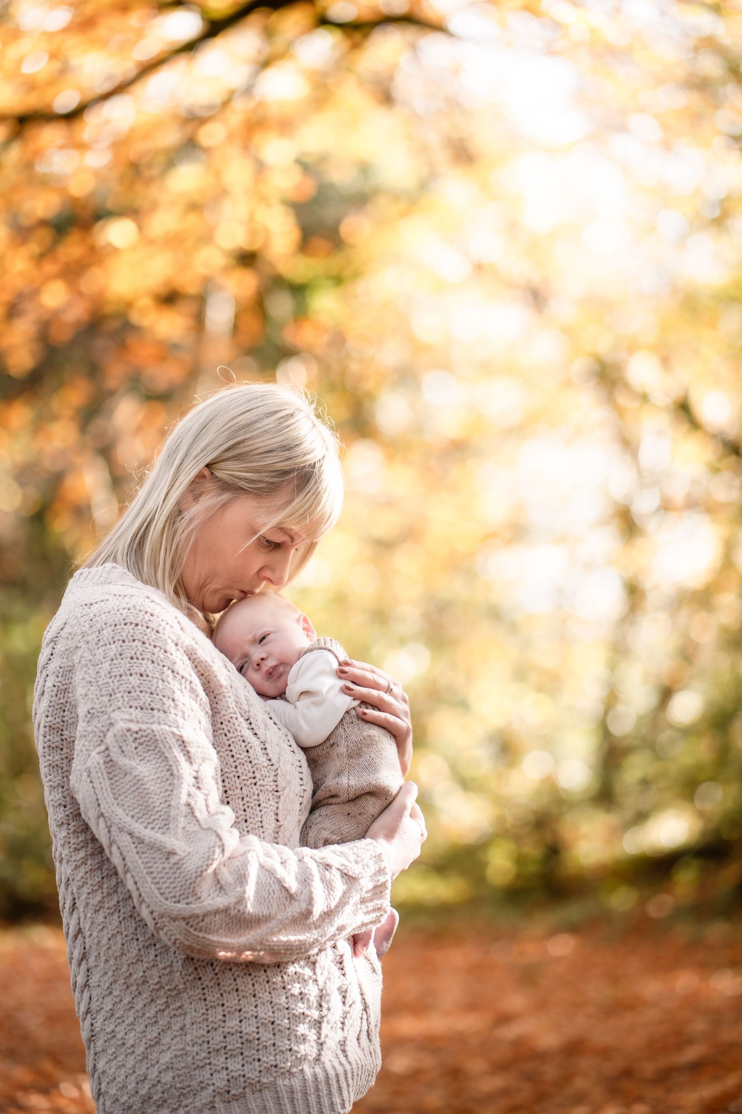 A tender autumn moment captured in golden sunlight with fallen leaves creating a warm seasonal backdrop.