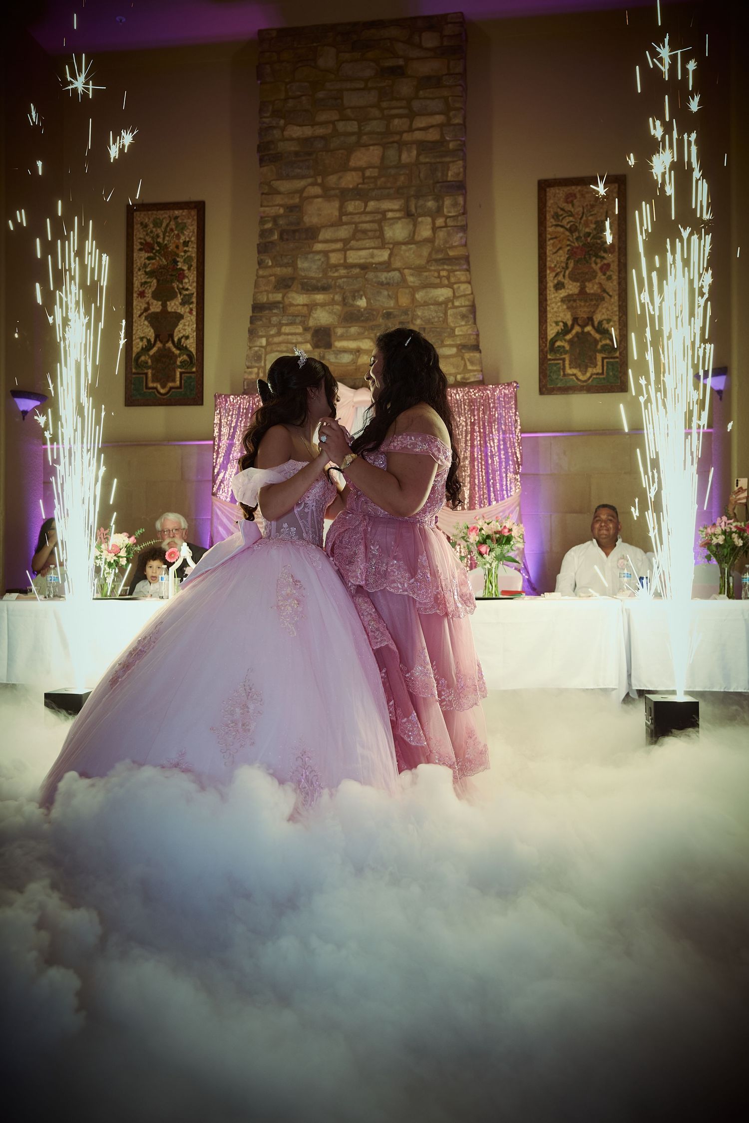 Wedding reception dance floor filled with fog and illuminated by purple lights and sparkler fountains during first dance.