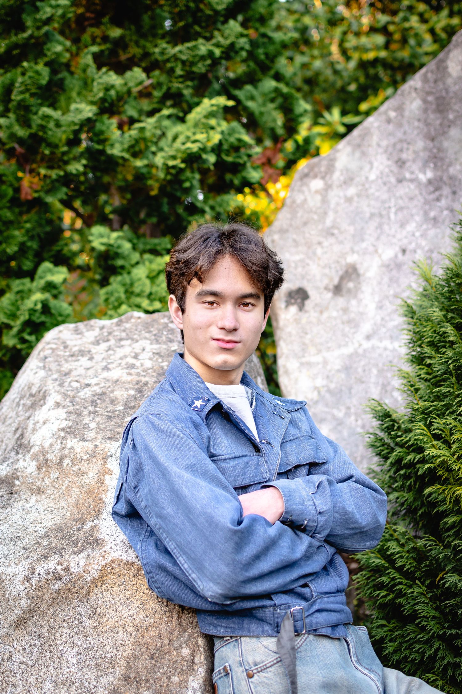 Seattle senior leaning against rock formation at Kubota Garden entrance during afternoon session