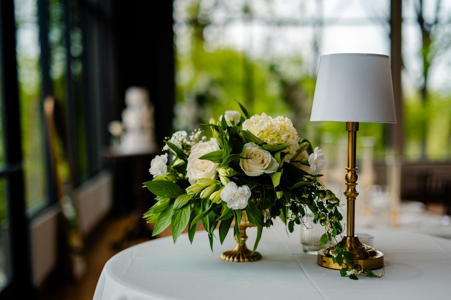 A rustic wedding reception table features white linens, floral centerpieces, and elegant place settings in a natural setting.