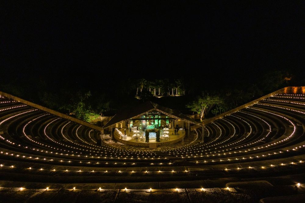 An illuminated amphitheater at night with concentric rows of lights creating a magical circular pattern.