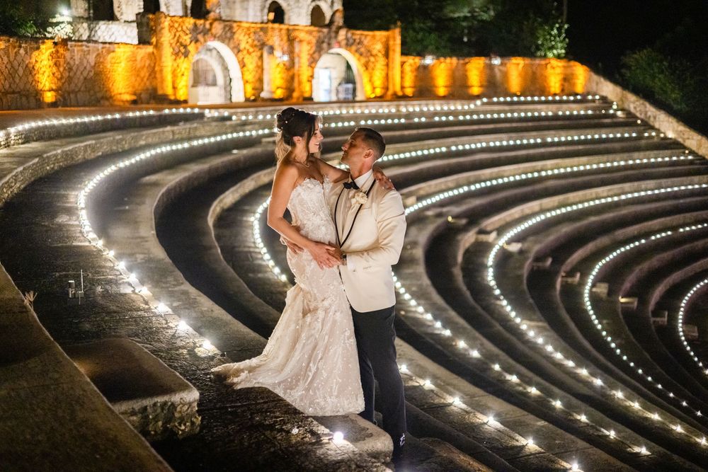 A romantic couple dances on an illuminated outdoor terrace with a glowing castle in the background at night.