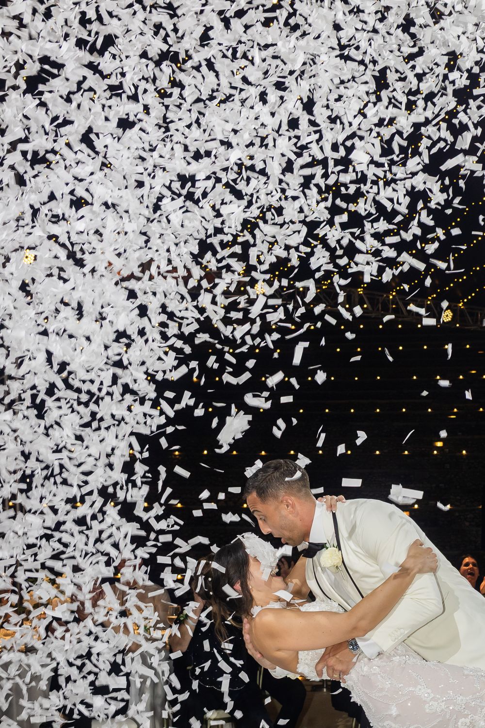 A sequence showing a person falling backwards into a cloud of white confetti against a black background.