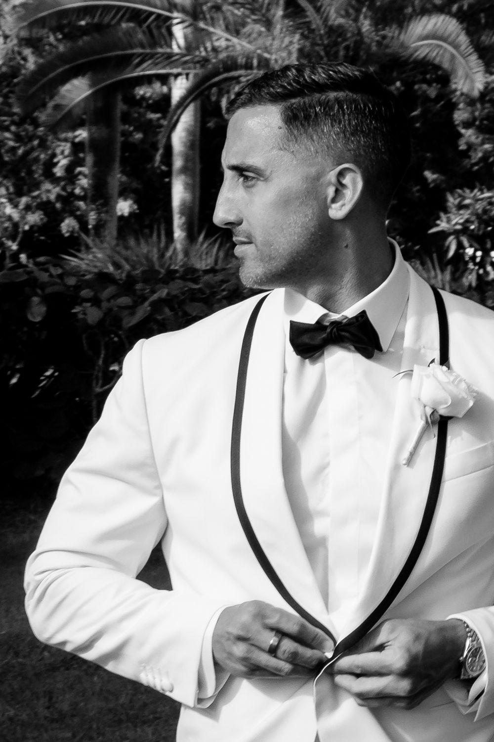 A person in a white tuxedo jacket and black bow tie adjusts their collar in a series of black and white photos.
