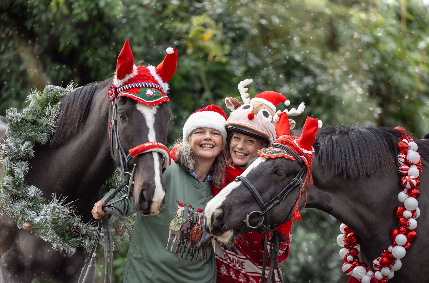 A horse wearing a festive Christmas wreath and Santa hat stands with someone in holiday attire for seasonal photos.