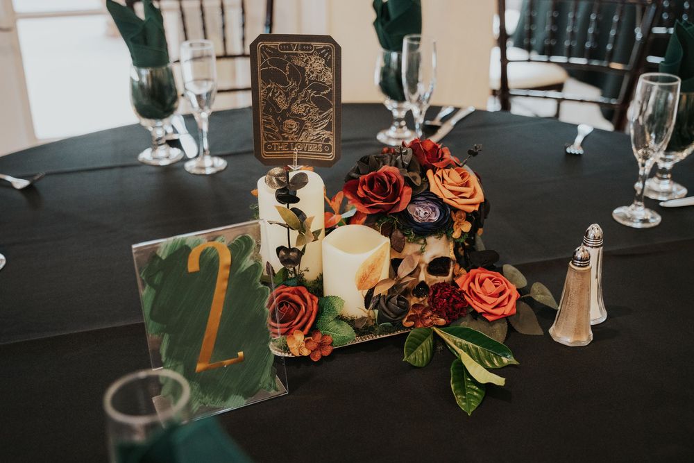 Wedding reception table settings with elegant floral centerpieces and wine glasses on dark tablecloths.