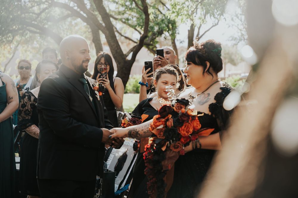 Wedding guests gather around a violin player performing outdoors during a celebration ceremony.