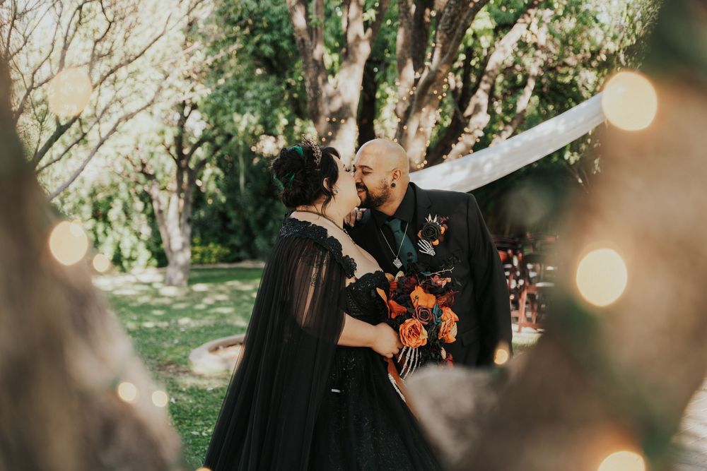 A couple embraces in a sun-dappled forest setting during an intimate wedding ceremony.