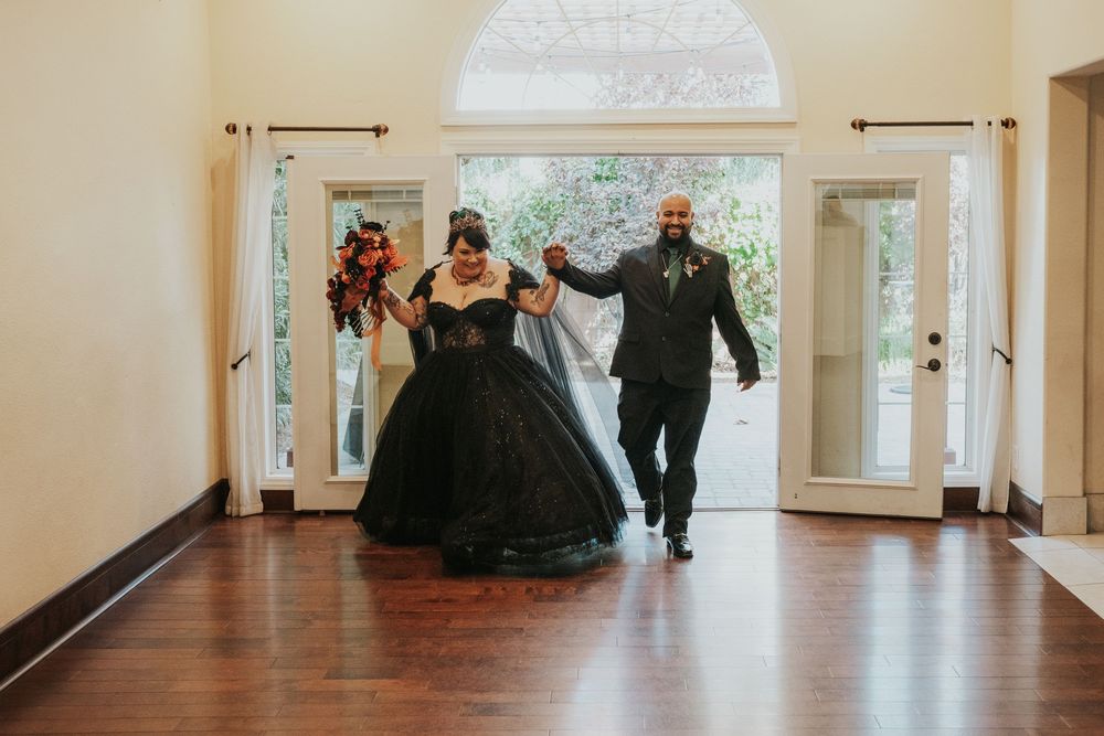 People slide across a polished hardwood floor in a bright hallway with white walls and large windows.
