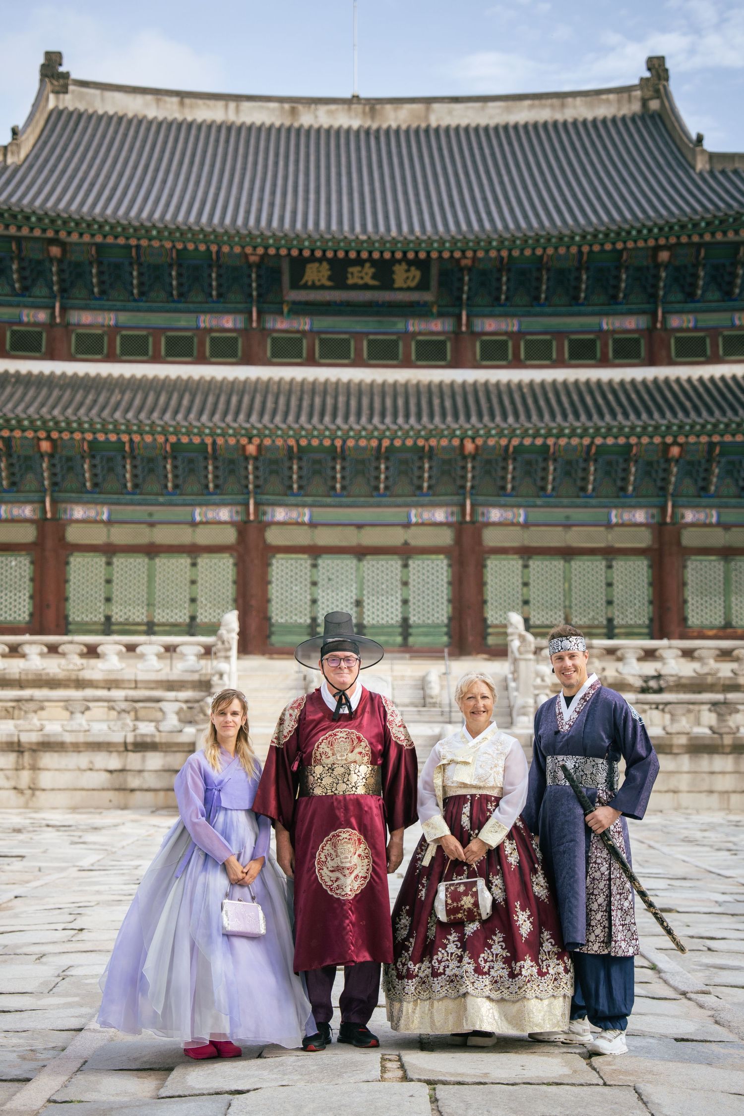 A group wearing traditional Korean hanbok clothing poses at Changdeokgung Palace in Seoul.