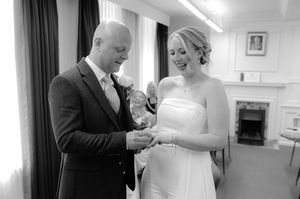 Black and white photo collage showing intimate moments during a wedding ceremony with ring exchanges and candid interactions.