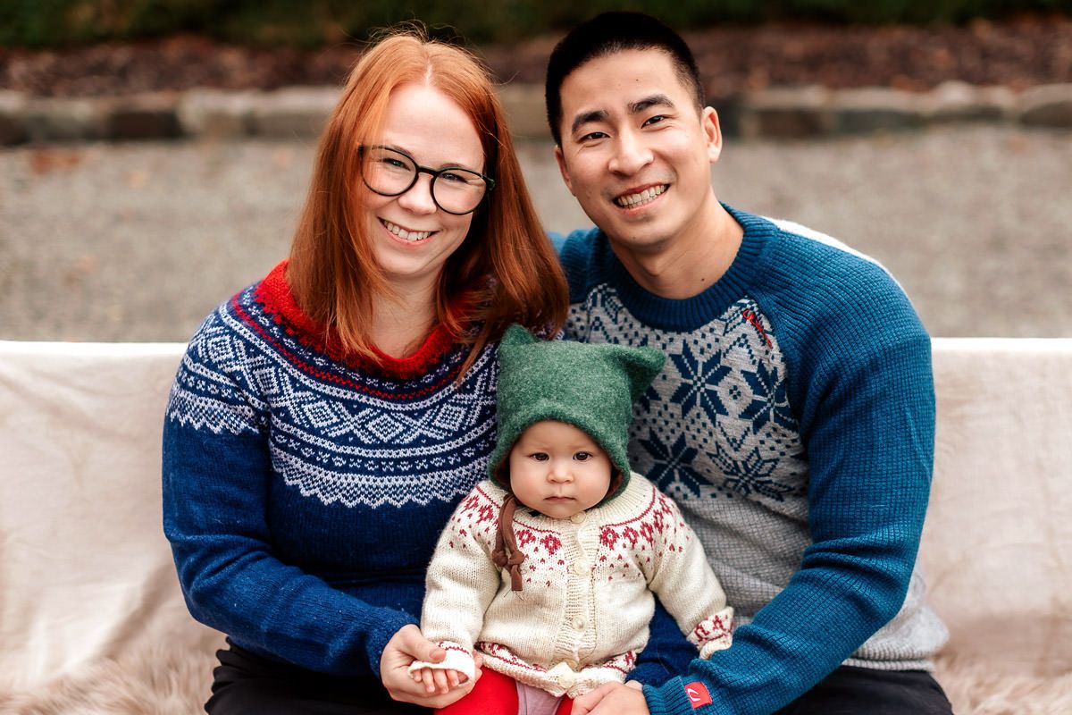 Mor, far og datter med strikkegensere på julekortfotografering på Ålgård med Ørstavik Foto. De sitter tett på en benk og smiler til kamera.