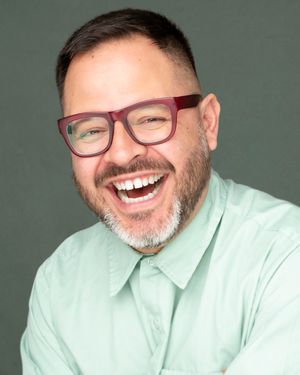 A person in a mint green button-down shirt and red glasses laughs joyfully in a series of expressive portraits.