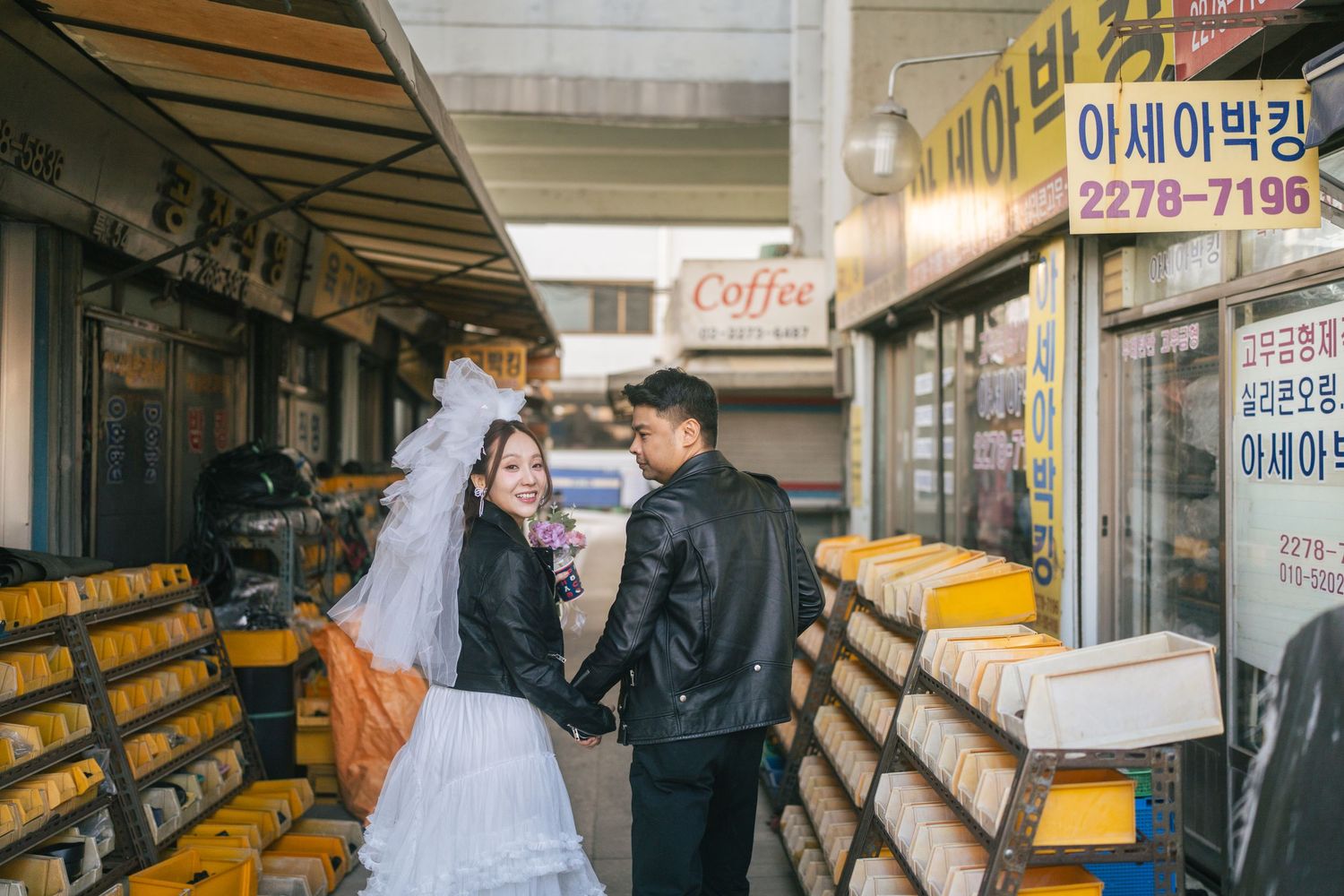 Customers browse through rows of books at a Korean bookstore with yellow spines displayed on wooden shelves.