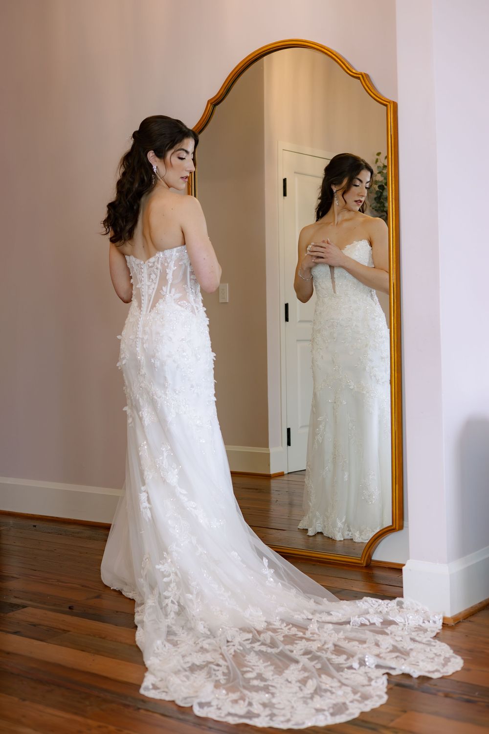A stunning white wedding dress with lace details and long train shown from multiple angles in a bridal fitting room.
