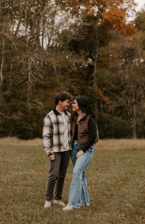 Couple sharing intimate moments in an autumn field with fall foliage.