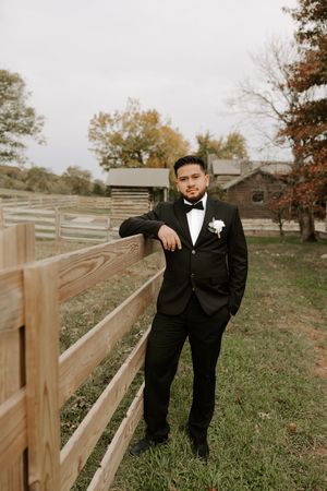 A formal portrait taken outdoors with wooden fencing and autumn trees in the background.
