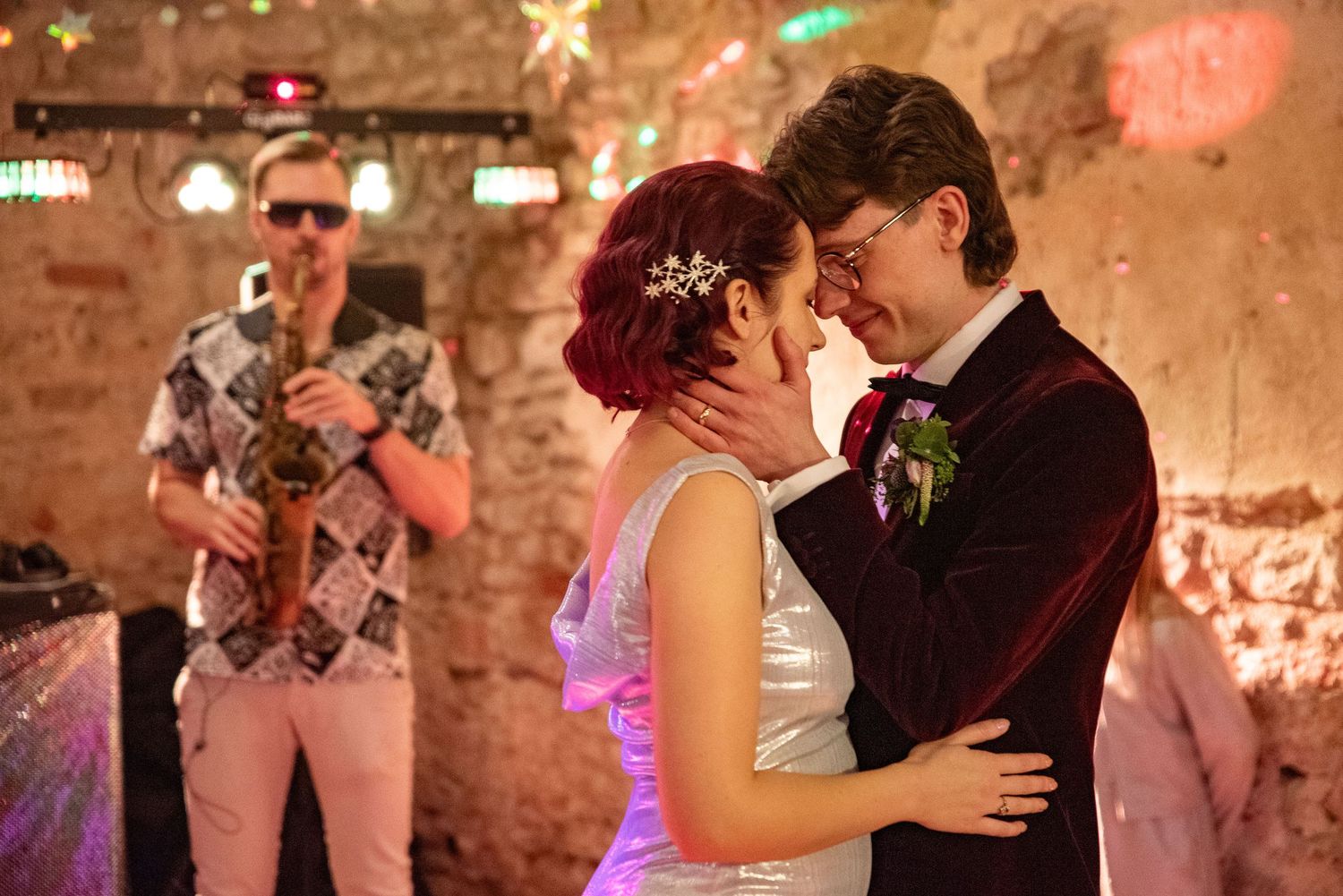 Couples dancing together at wedding reception with ambient lighting and brick walls.