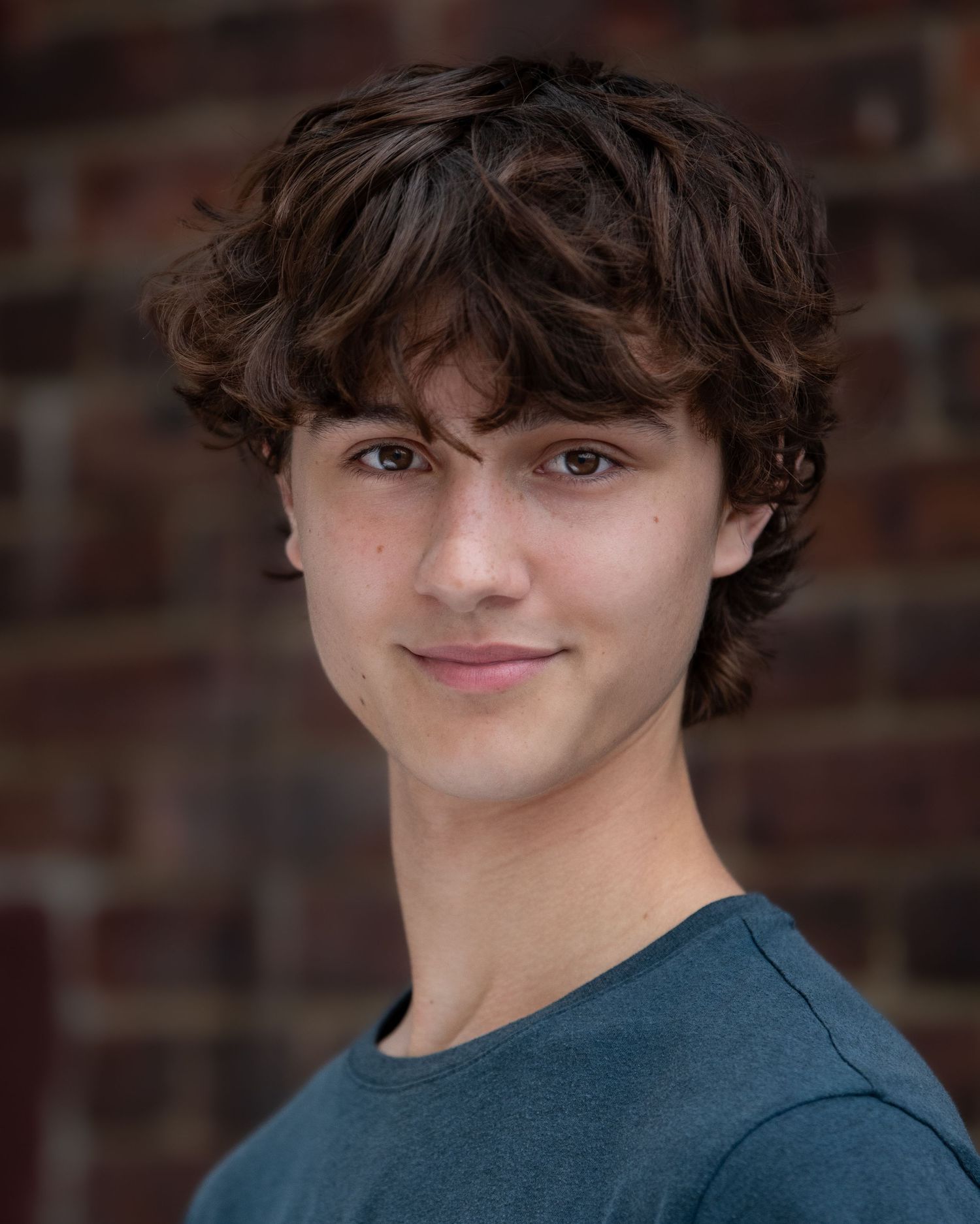 Headshot of boy against brick wall background in warm natural lighting in Atlantic Highlands NJ